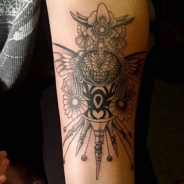 Ornate amulet with floral elements ornamental tattoo on the forearm by Chris