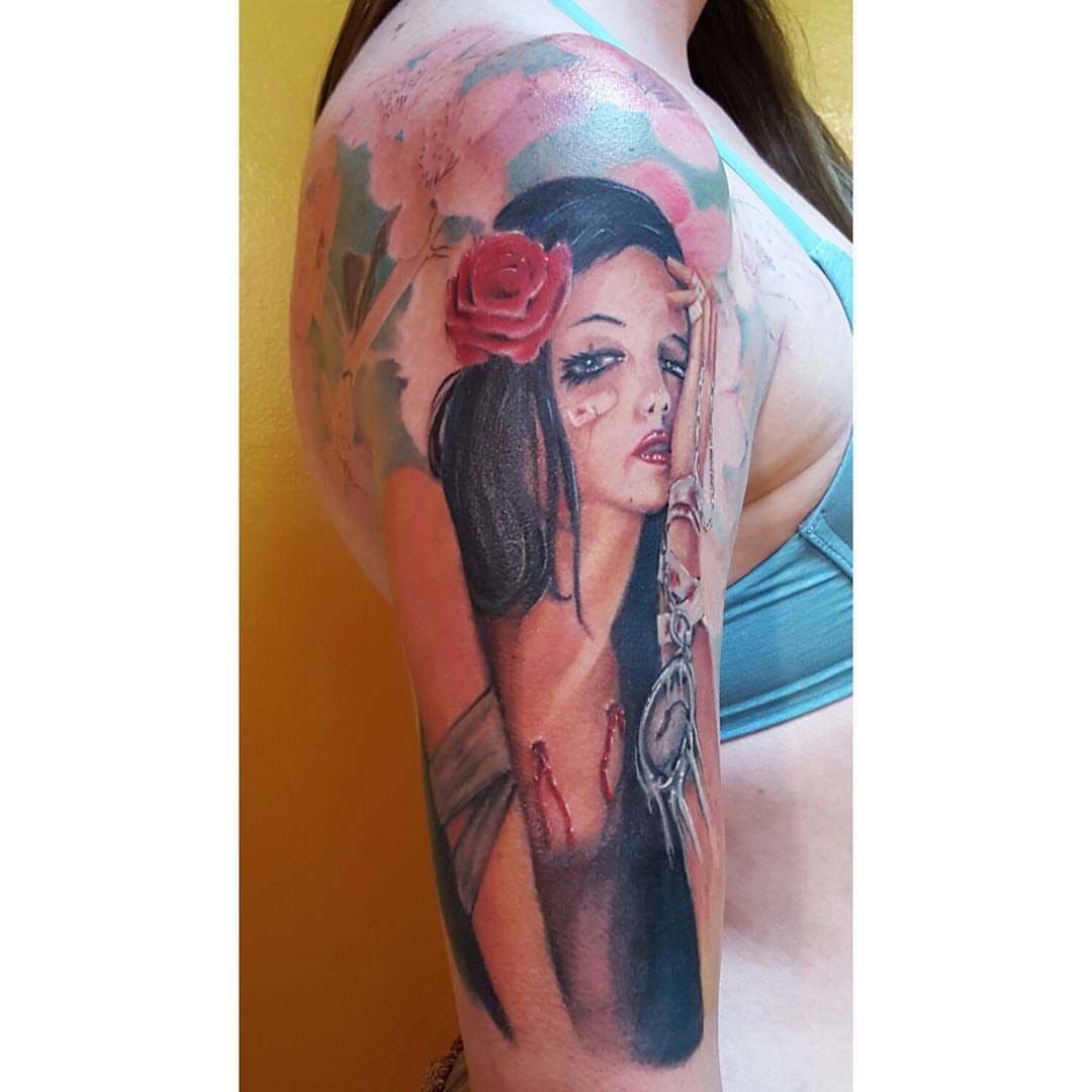 Woman with rose realism tattoo on the upper arm by Augie Stakes