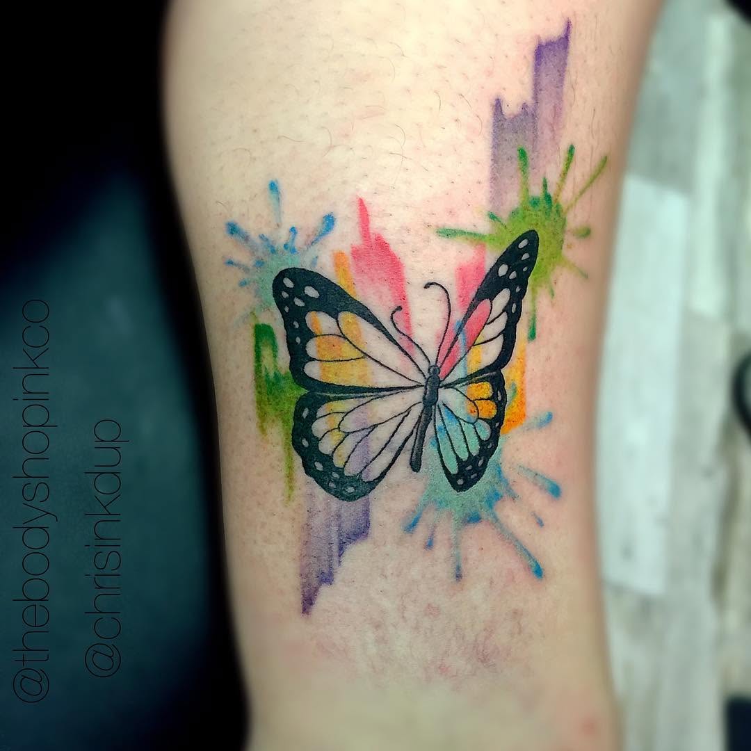 Butterfly with watercolor splashes watercolor tattoo on the forearm by Chris