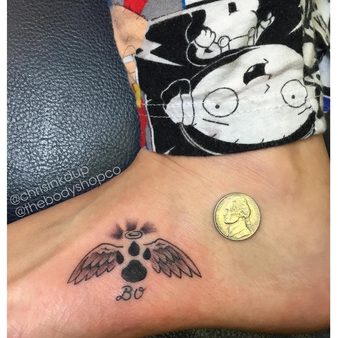 Paw print with wings and name realism tattoo on the foot by Chris