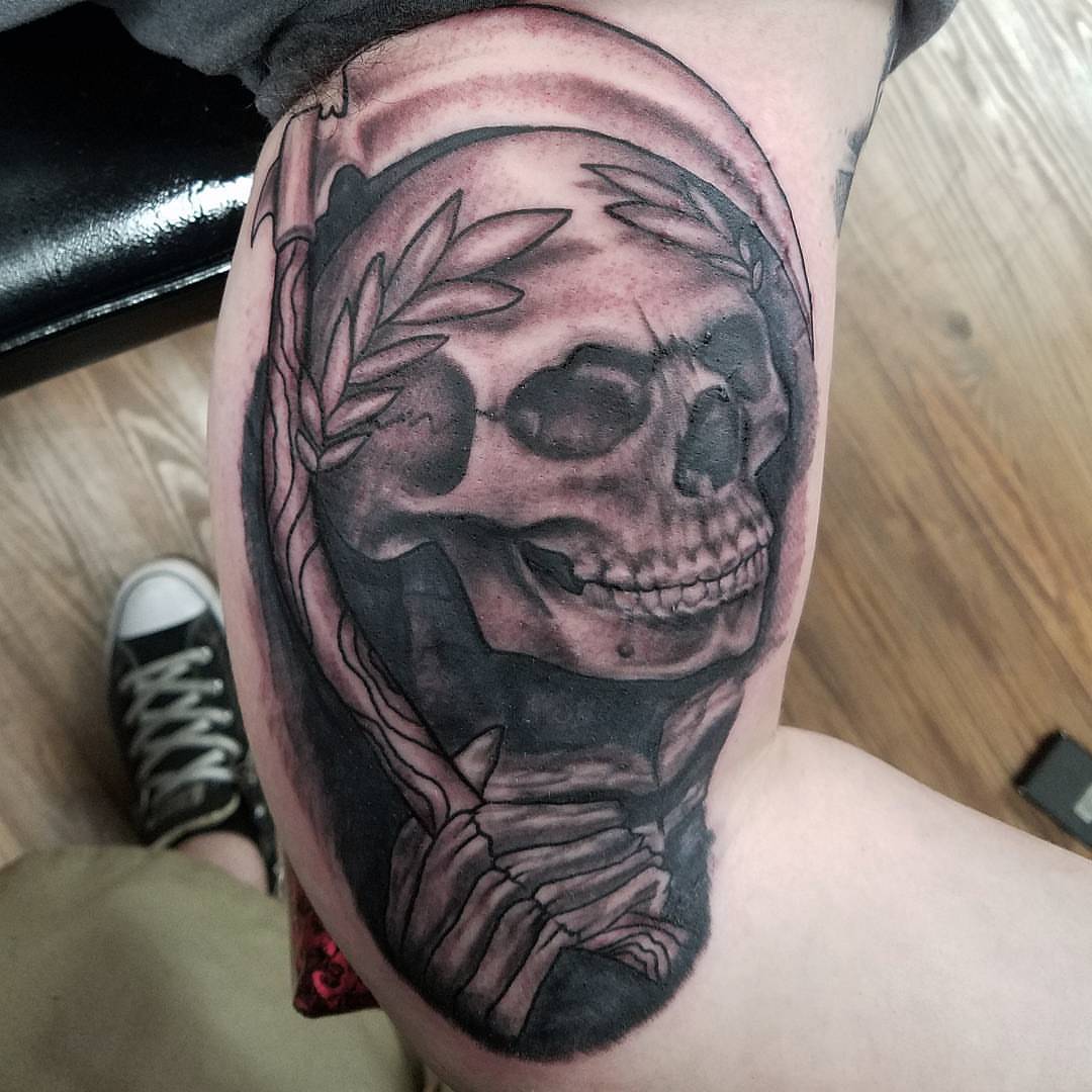 Skull with laurel wreath realism tattoo on the thigh by Dick Eckman