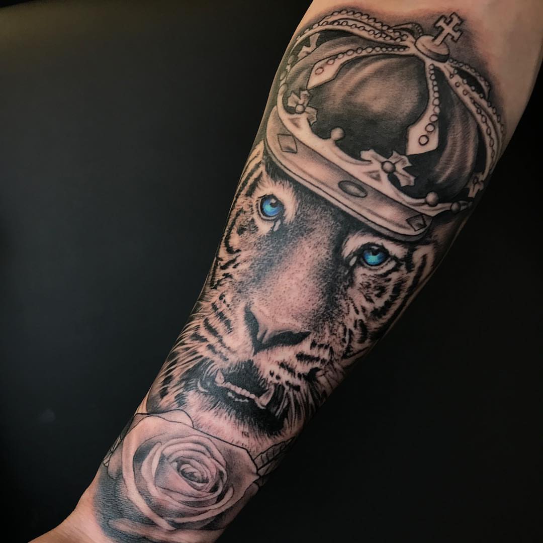 Lion wearing crown realism tattoo on the forearm by Joe Shepp