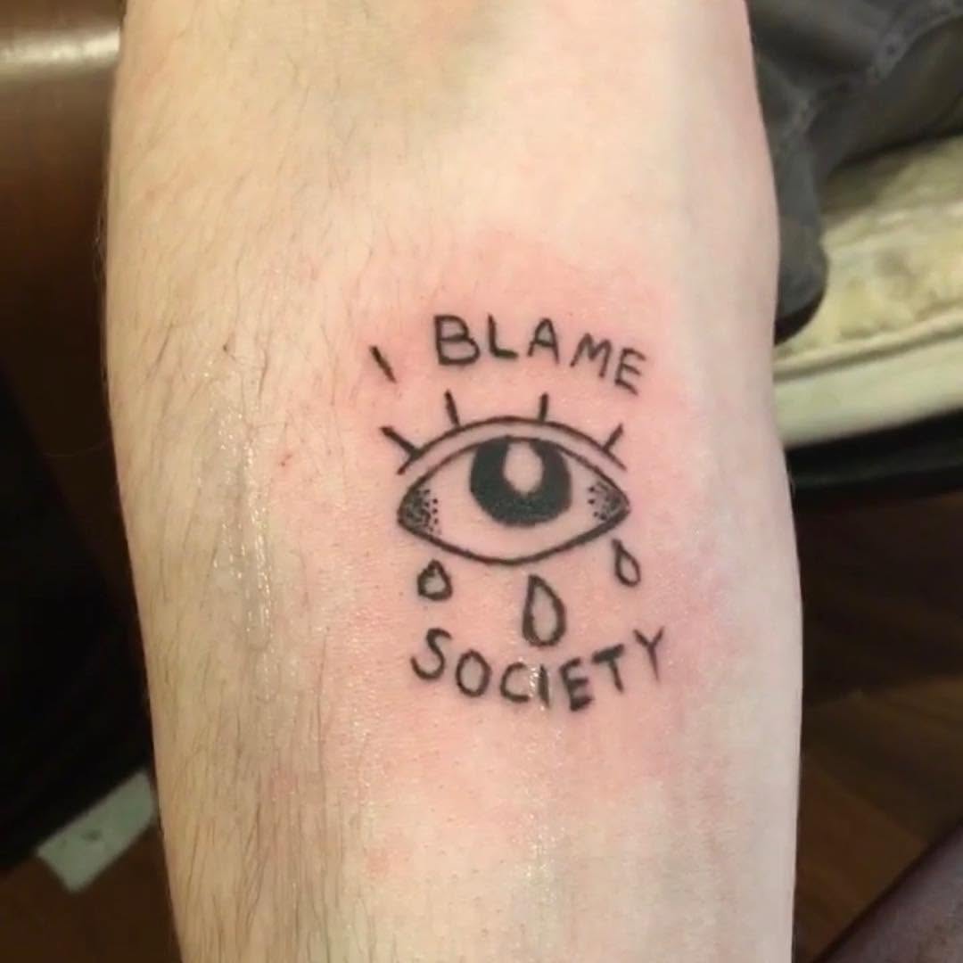 Eye with tears and text ignorant tattoo on the forearm by @beantowntats