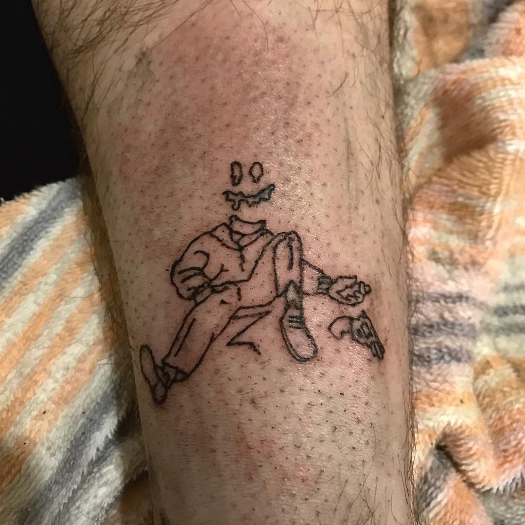 Headless figure with gun tattoo on the forearm by @beantowntats
