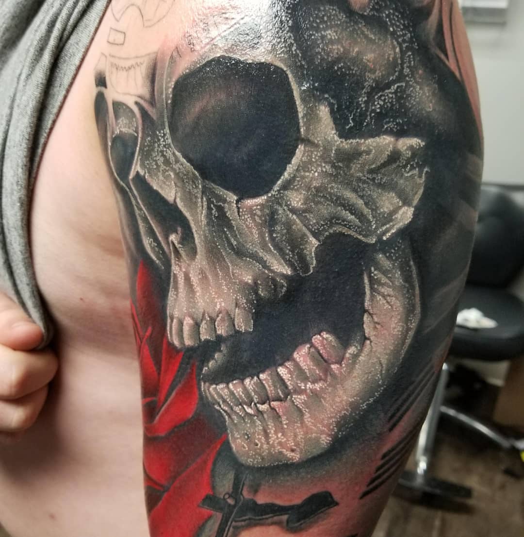 Grinning skull dark realism tattoo on the chest by Jon Goad