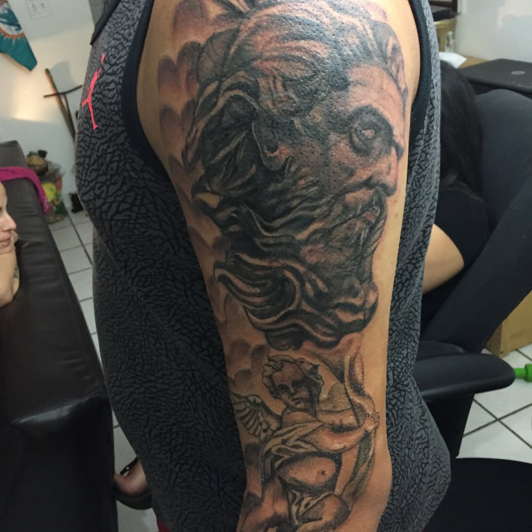God and cherub realism tattoo on the upper arm by Junior Trevino