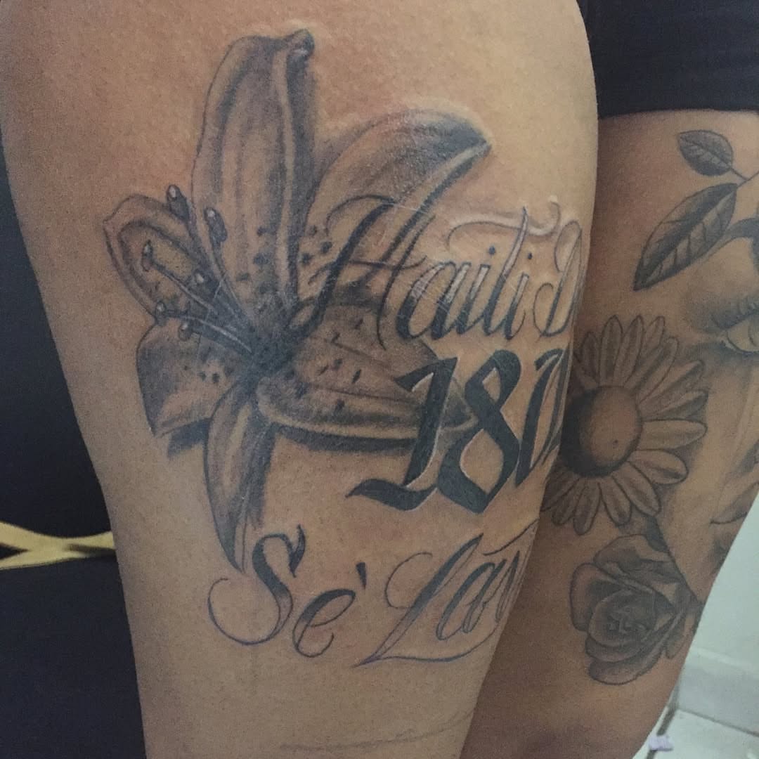 Lily and script black and grey tattoo on the forearm by Junior Trevino