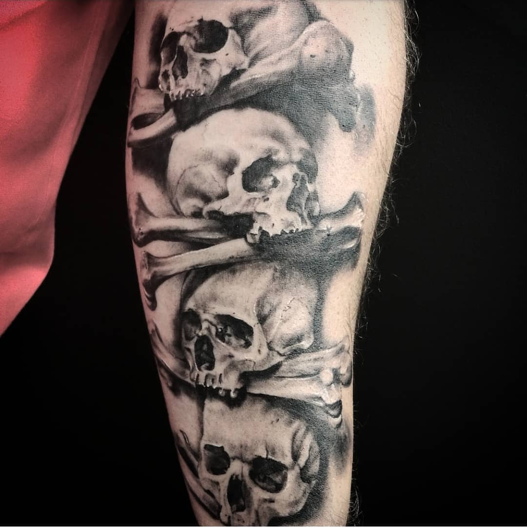 Skulls and bones realism tattoo on the forearm by Lindsay