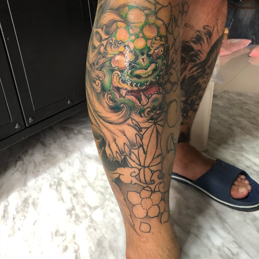 Foo dog and flowers Japanese tattoo on the calf by 中国🇨🇳沈阳513TATTOO