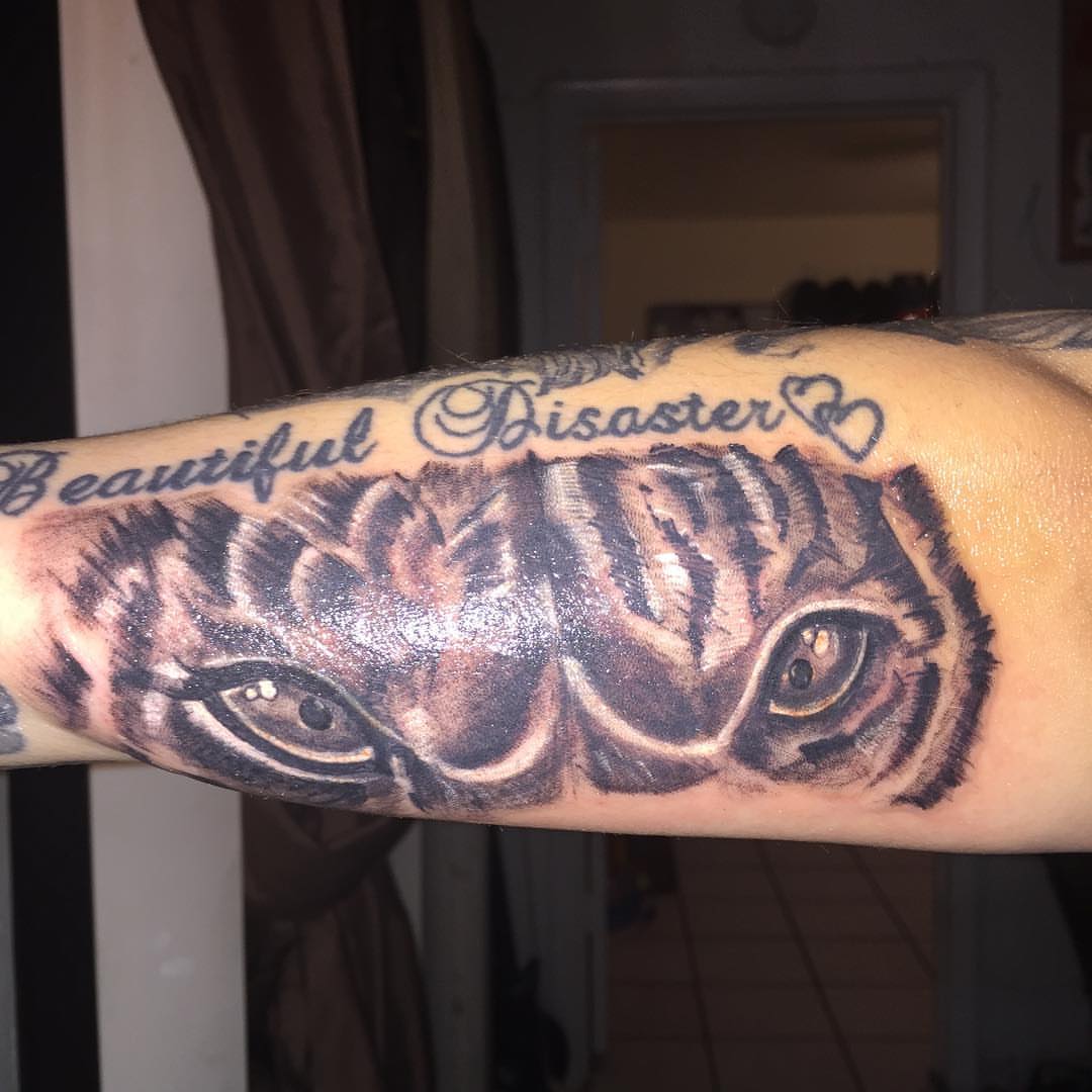 Tiger eyes realism tattoo on the forearm by Junior Trevino