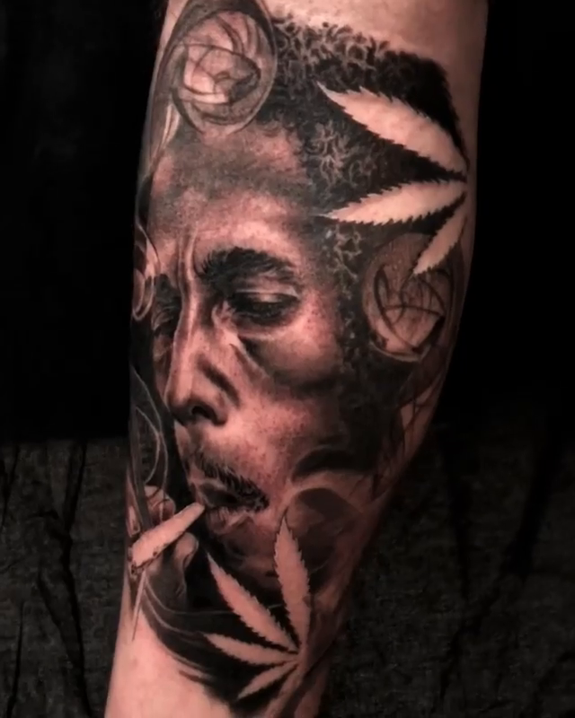 Bob Marley portrait with cannabis leaves realism tattoo by Carlos Macedo Tattoo