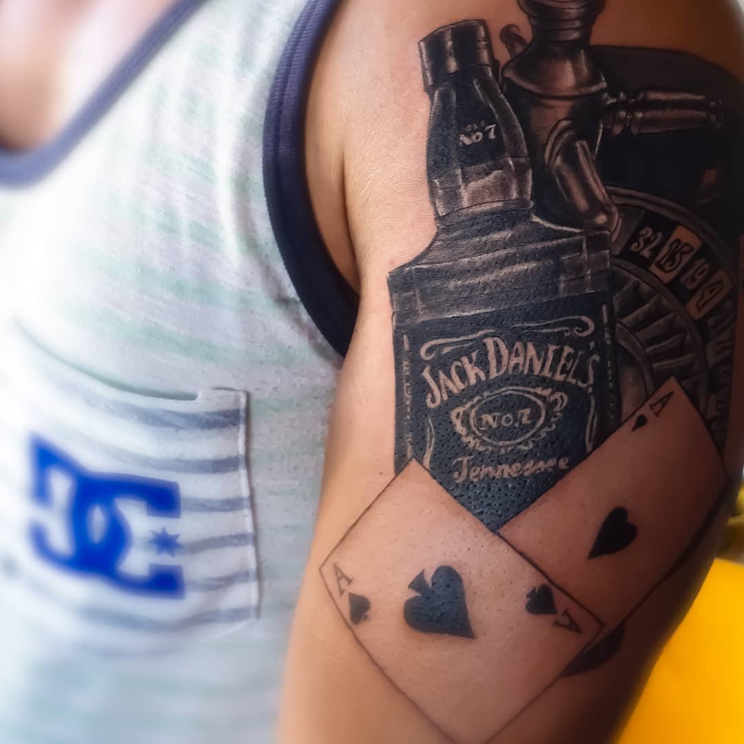 Jack daniels bottle and playing card realism tattoo on the forearm by 212tattoomalaga, Málaga, Spain