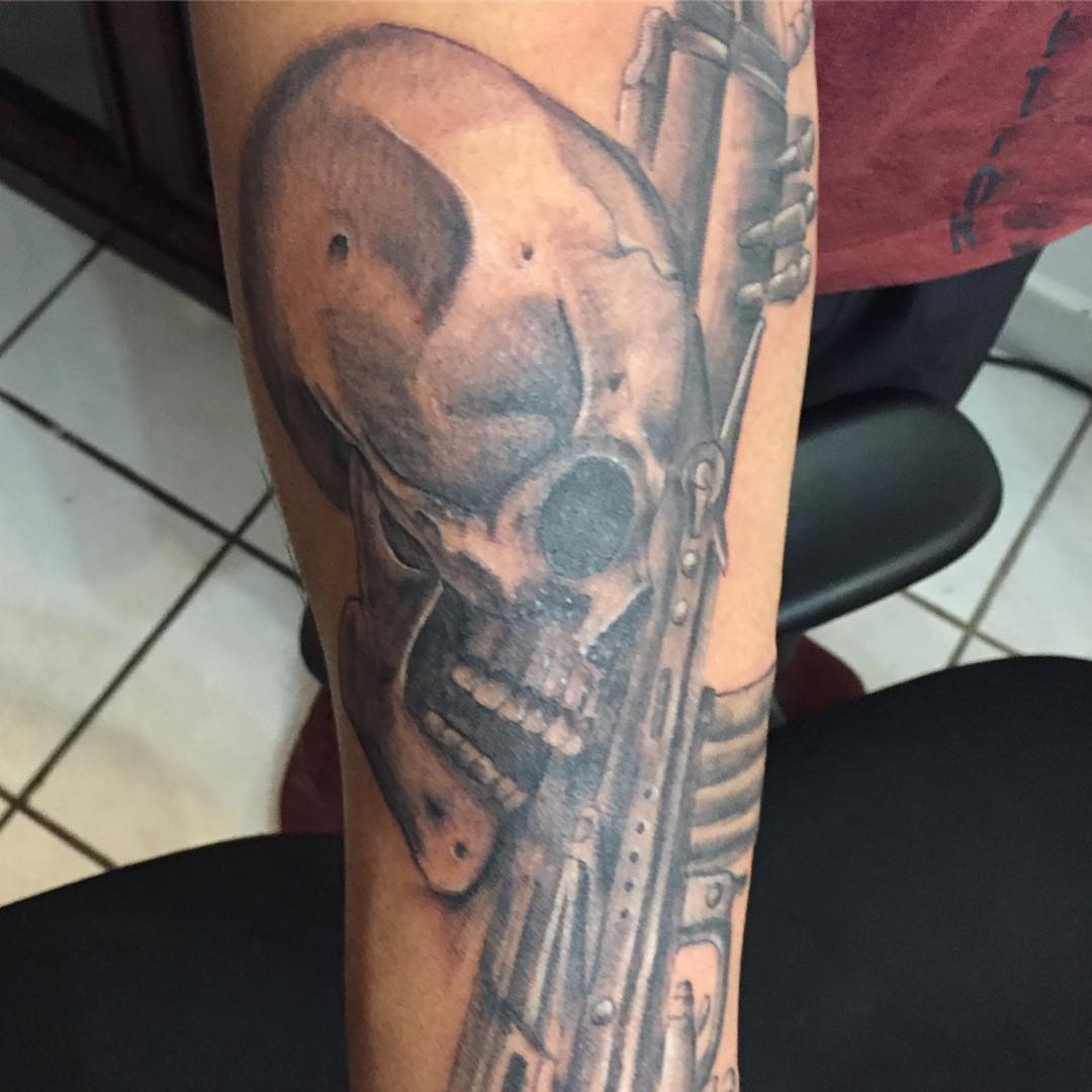 Skull and gun realism tattoo on the forearm by Junior Trevino