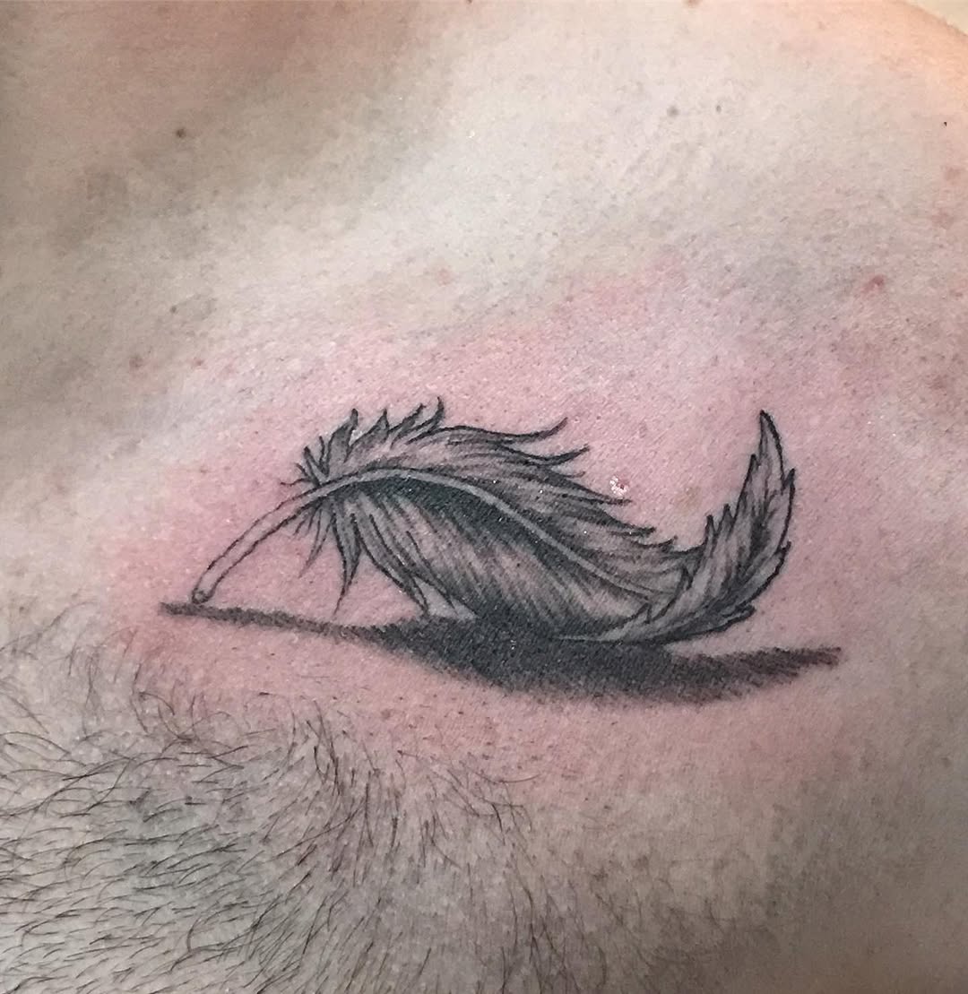 Feather with shadow realism tattoo on the shoulder by Chris