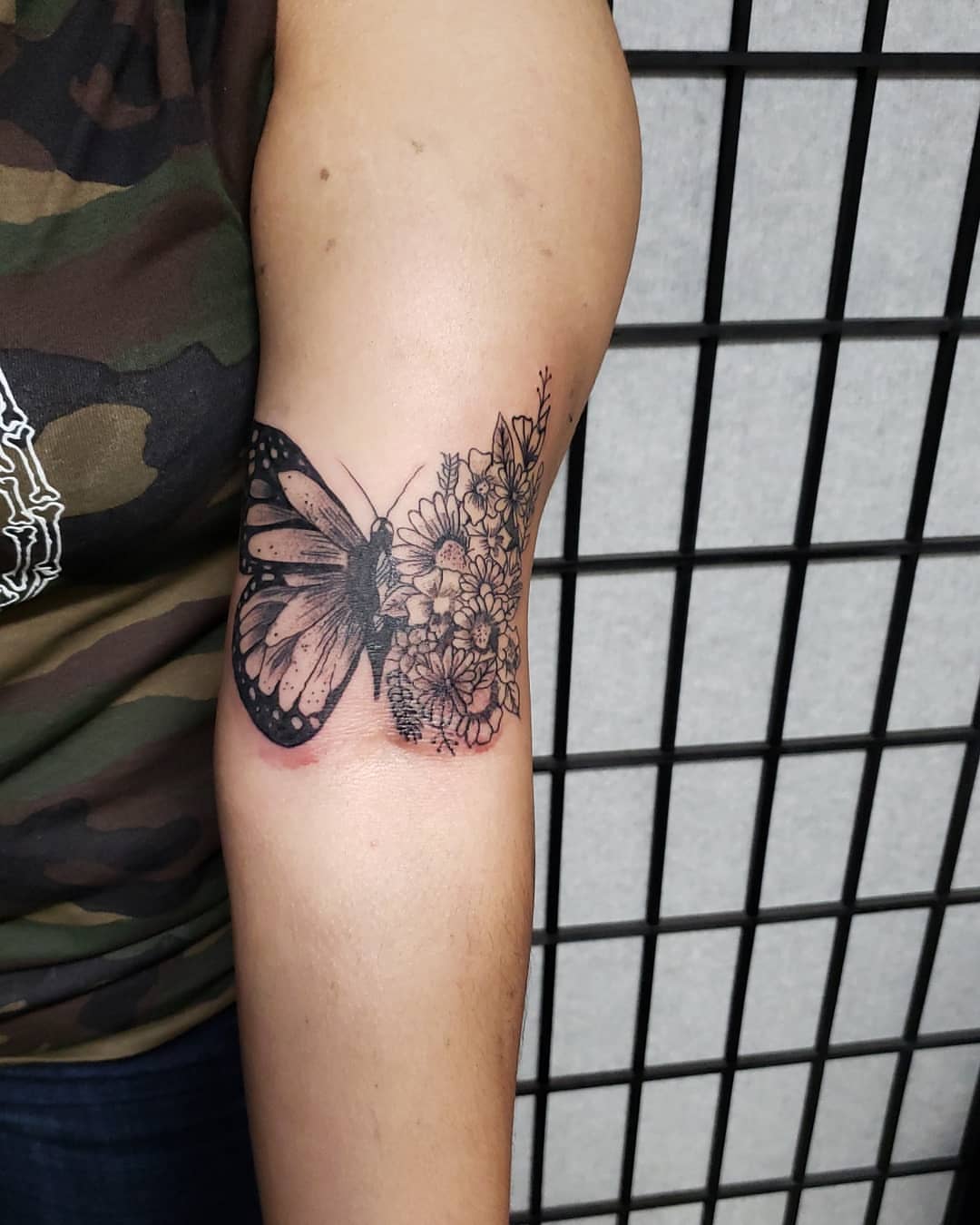Butterfly and flowers black and grey tattoo on the forearm by Eddy