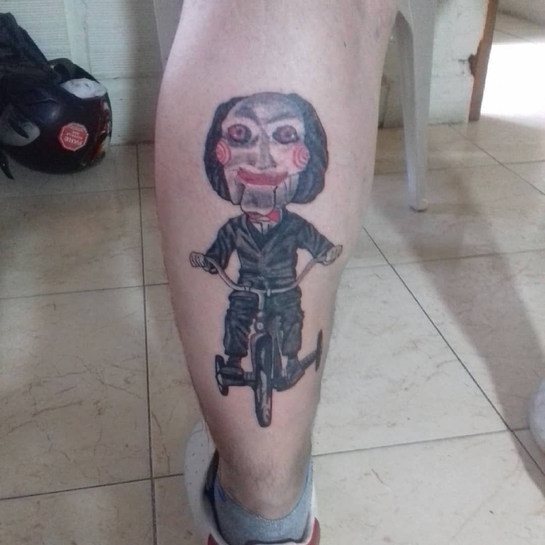 Jigsaw character on bicycle dotwork tattoo on the calf by Erasmo Vasquez