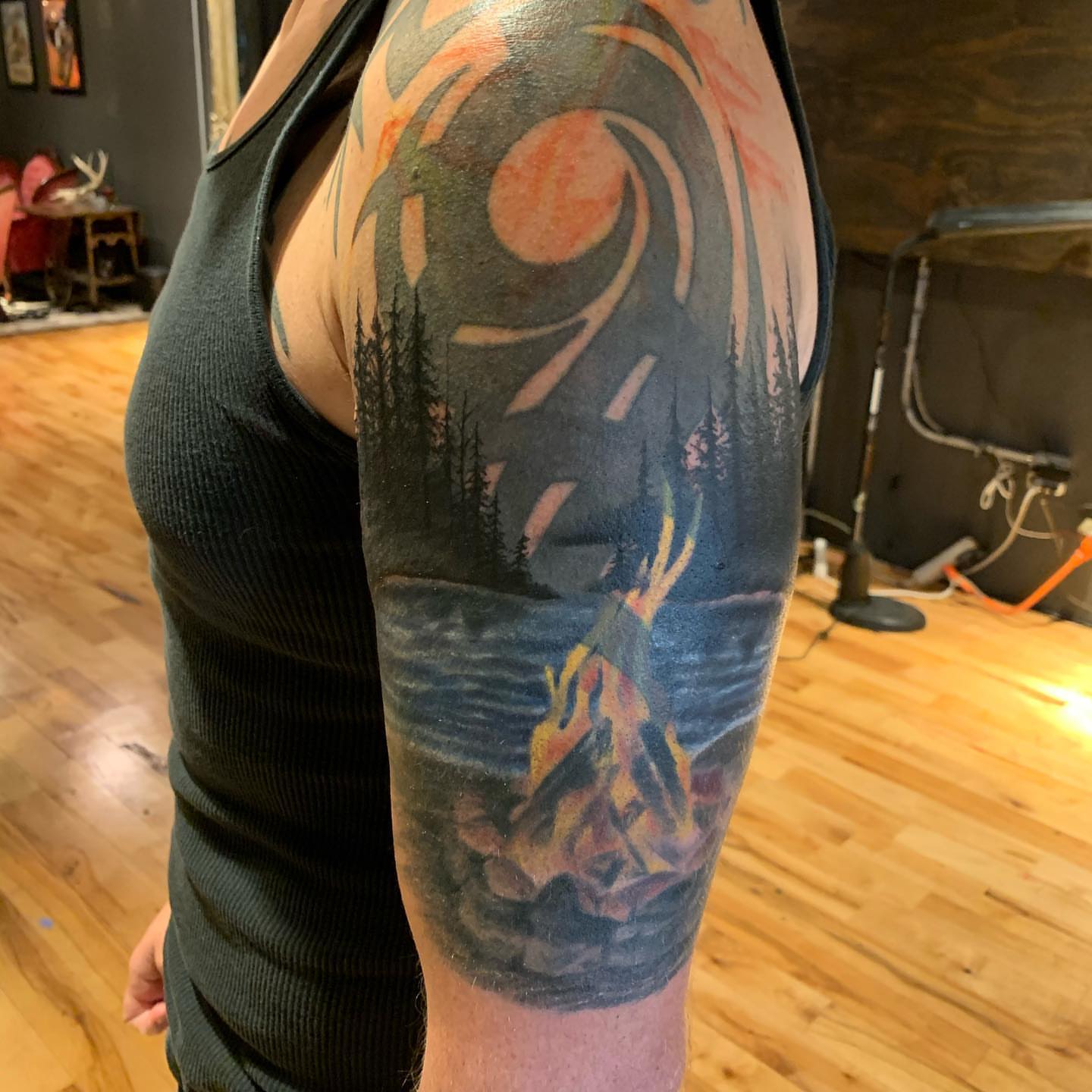 Campfire scene realism tattoo on the upper arm by Jeff Kees