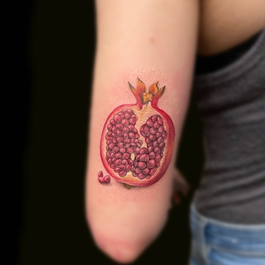 Pomegranate realism tattoo on the forearm by Madison Ast Tattoo