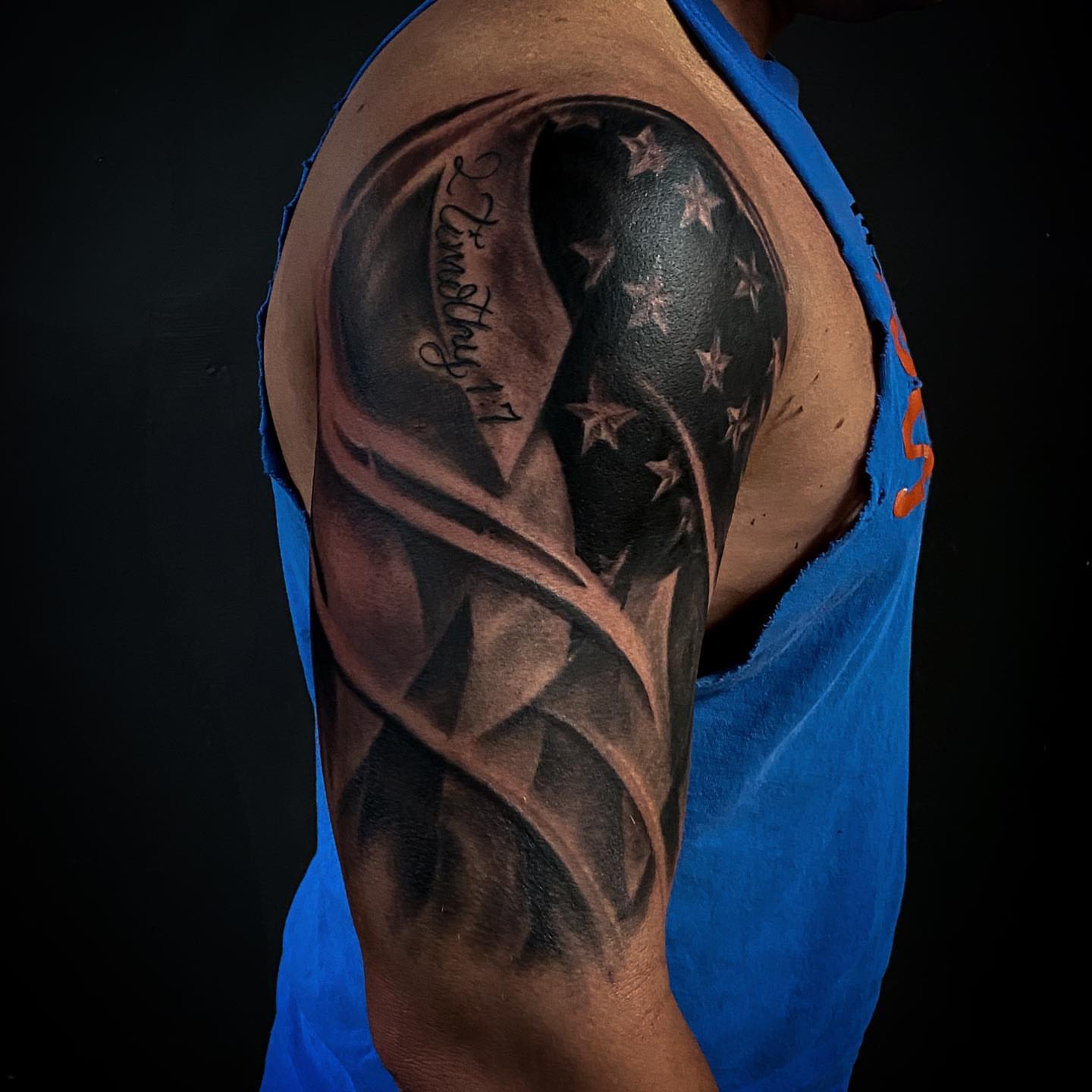 Flag and feather geometric tattoo on the upper arm by Jeff Kees