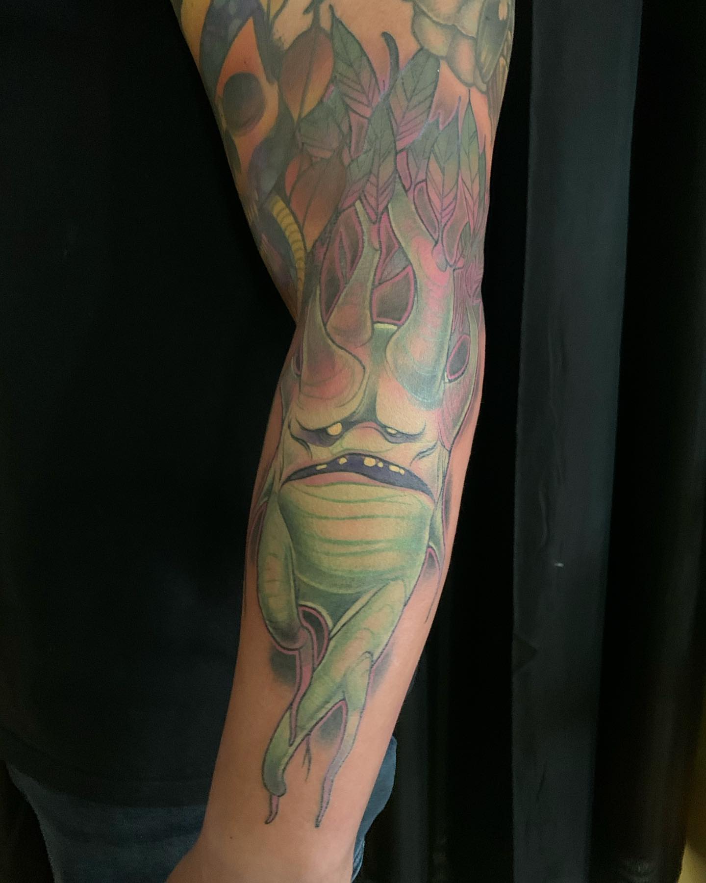 Mask with leaves new school tattoo on the forearm by Ben Viamontes