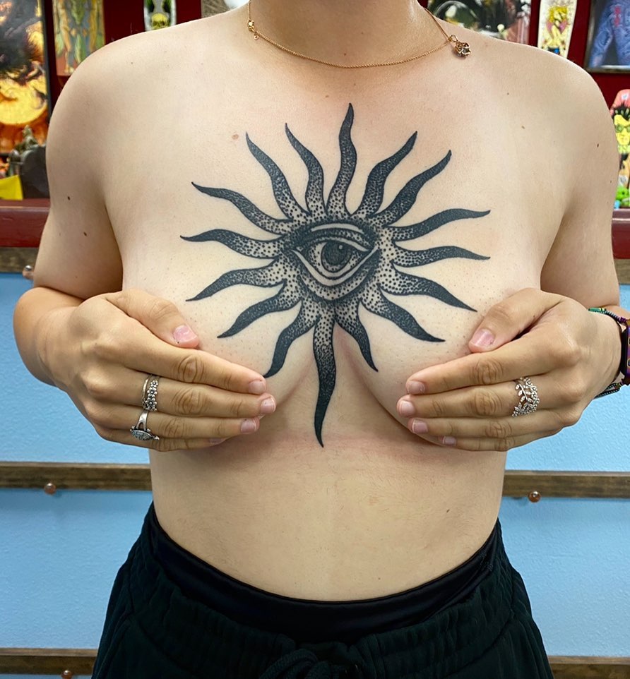 Eye with sun rays dotwork tattoo on the chest by Payton Prentice