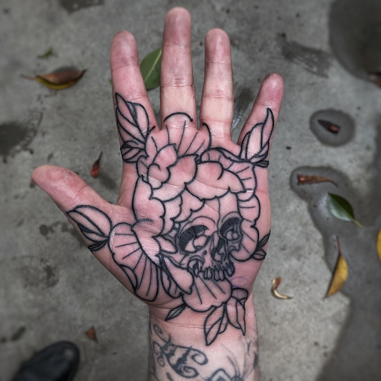 Skull and roses black and grey tattoo on the hand by Mark Walker