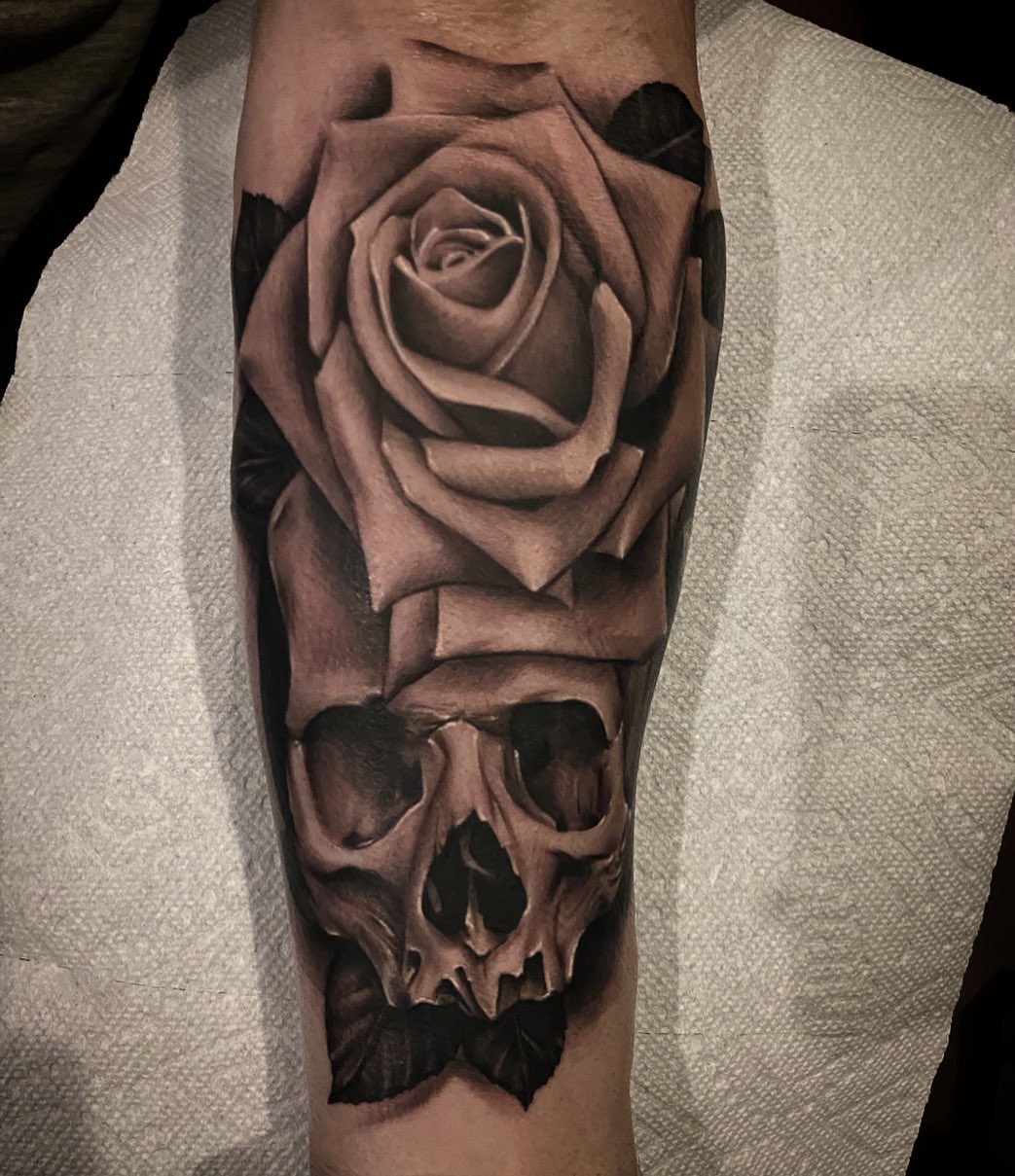 Rose and skull realism tattoo on the forearm by Dale DeVille
