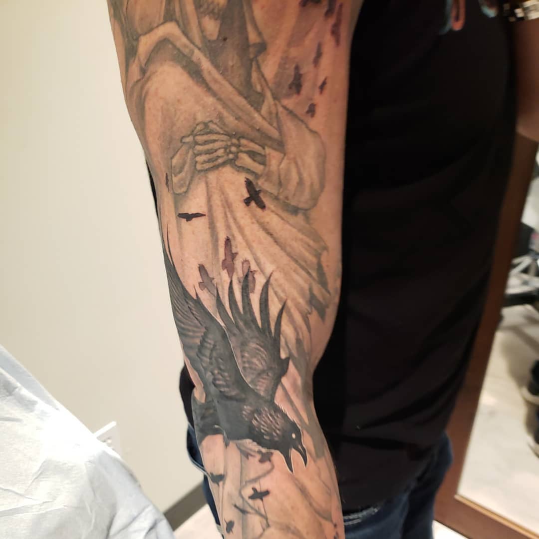Religious figure with crow realism tattoo on the forearm by @doctorze