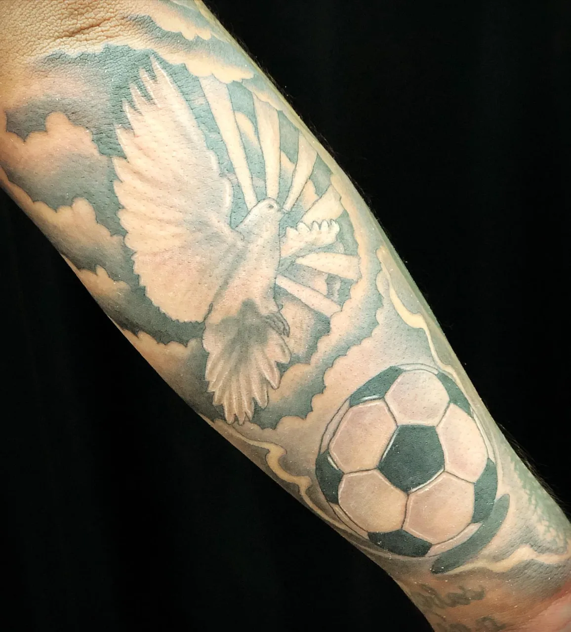Soccer ball and dove American traditional tattoo on the forearm by Charlie Soto
