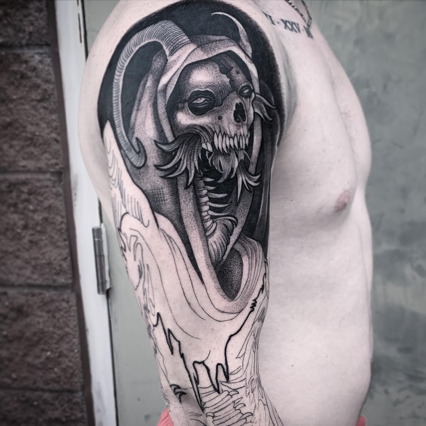 Skull realism tattoo on the upper arm by Briana Walker