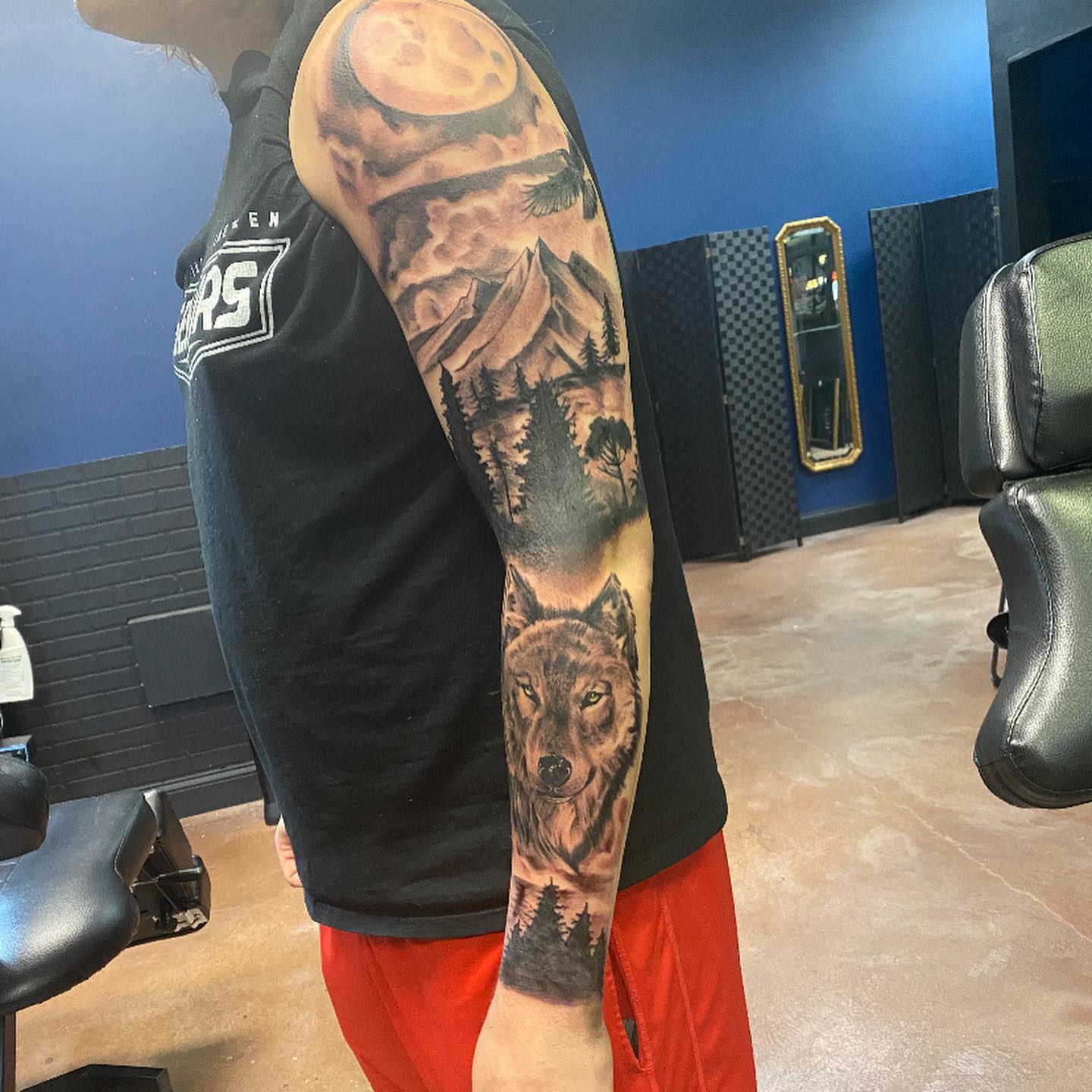 Wolf and mountain landscape realism tattoo on the upper arm by Mikeyftsk2