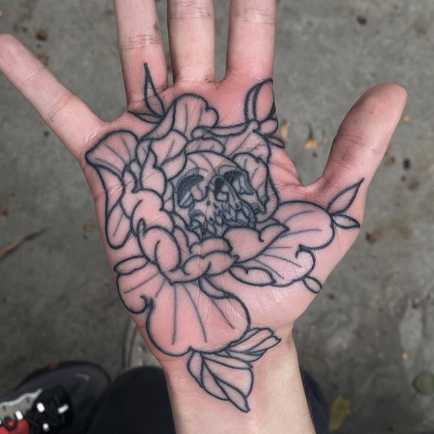 Flower with skull black and grey tattoo on the hand by Mark Walker