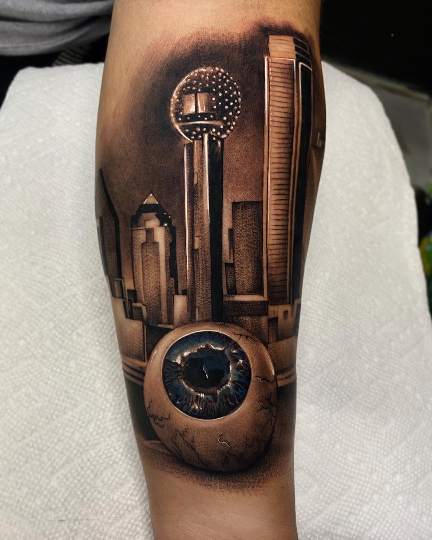 Cityscape with eye realism tattoo on the forearm by Ivan Guadalupe guzman
