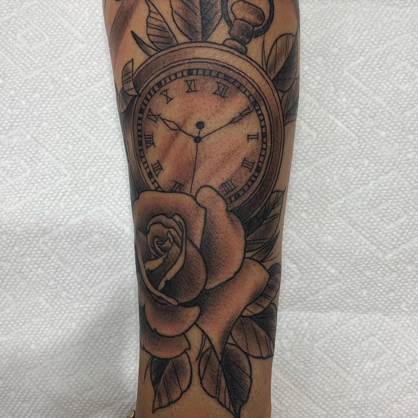 Clock and rose black and grey tattoo on the forearm by E