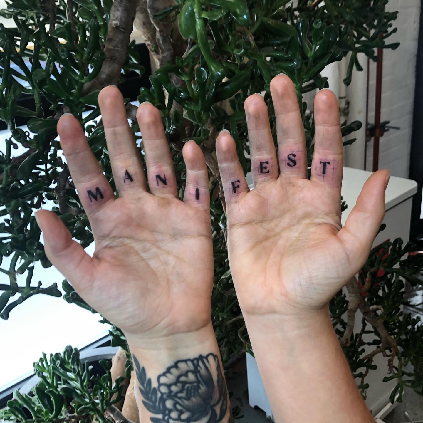 Manifest lettering script tattoo on the hand by @jettaturas, New City, New York