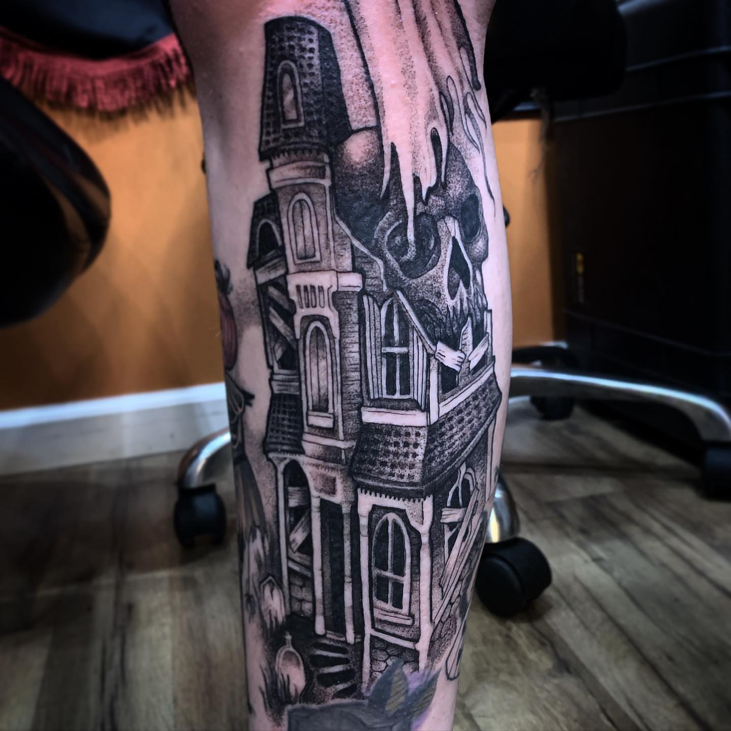 Haunted house with skull realism tattoo on the forearm by Briana Walker
