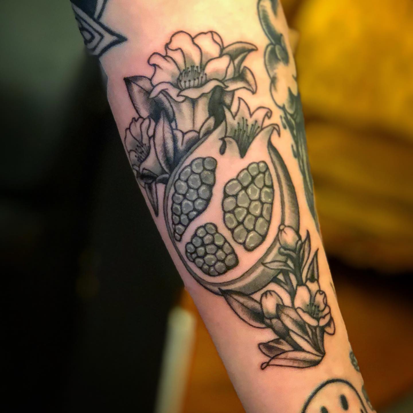 Pomegranate and flowers black and grey tattoo on the forearm by Dave Shurman