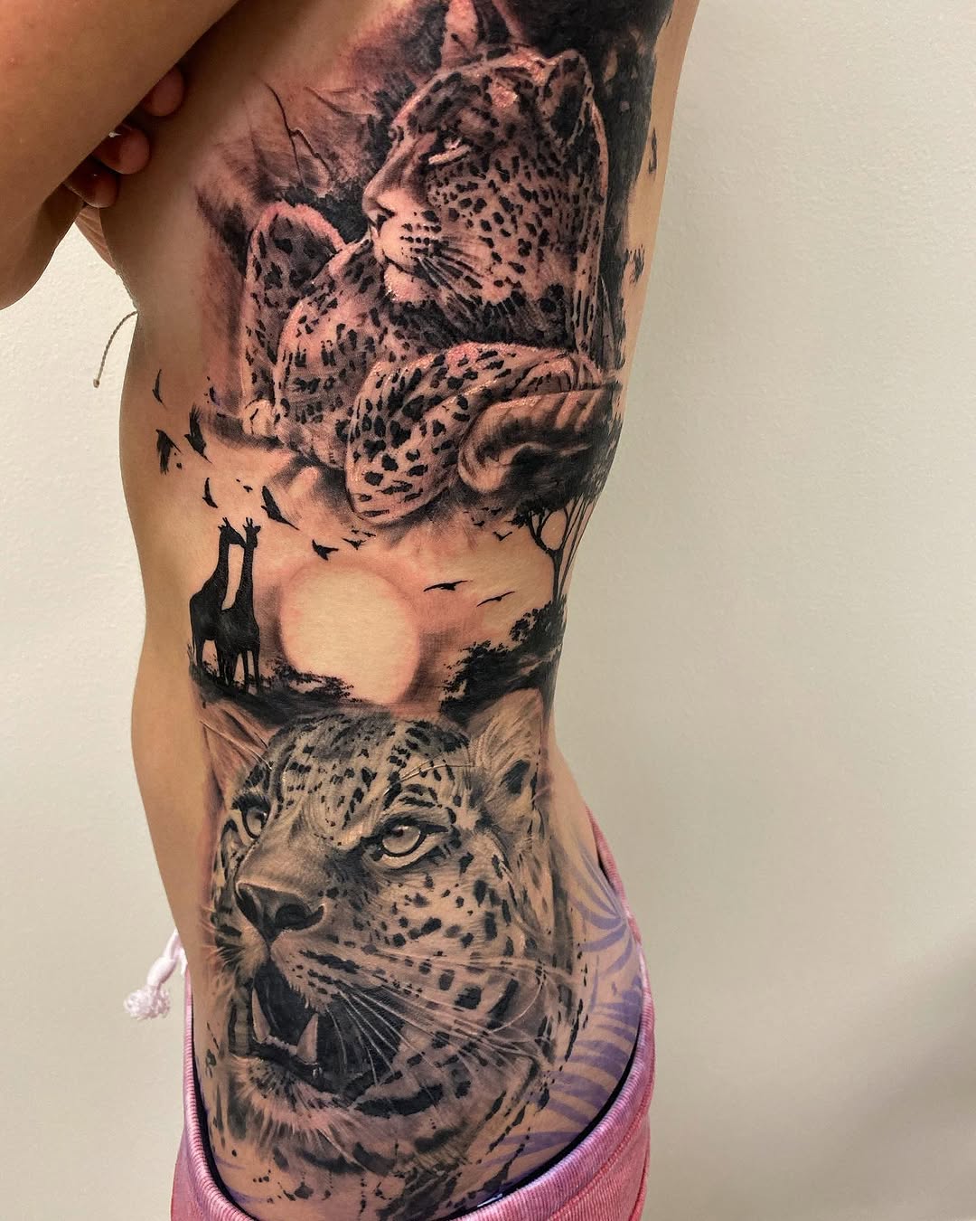 Leopards and giraffes on savanna realism tattoo on the ribs by David Garner, Los Angeles, California