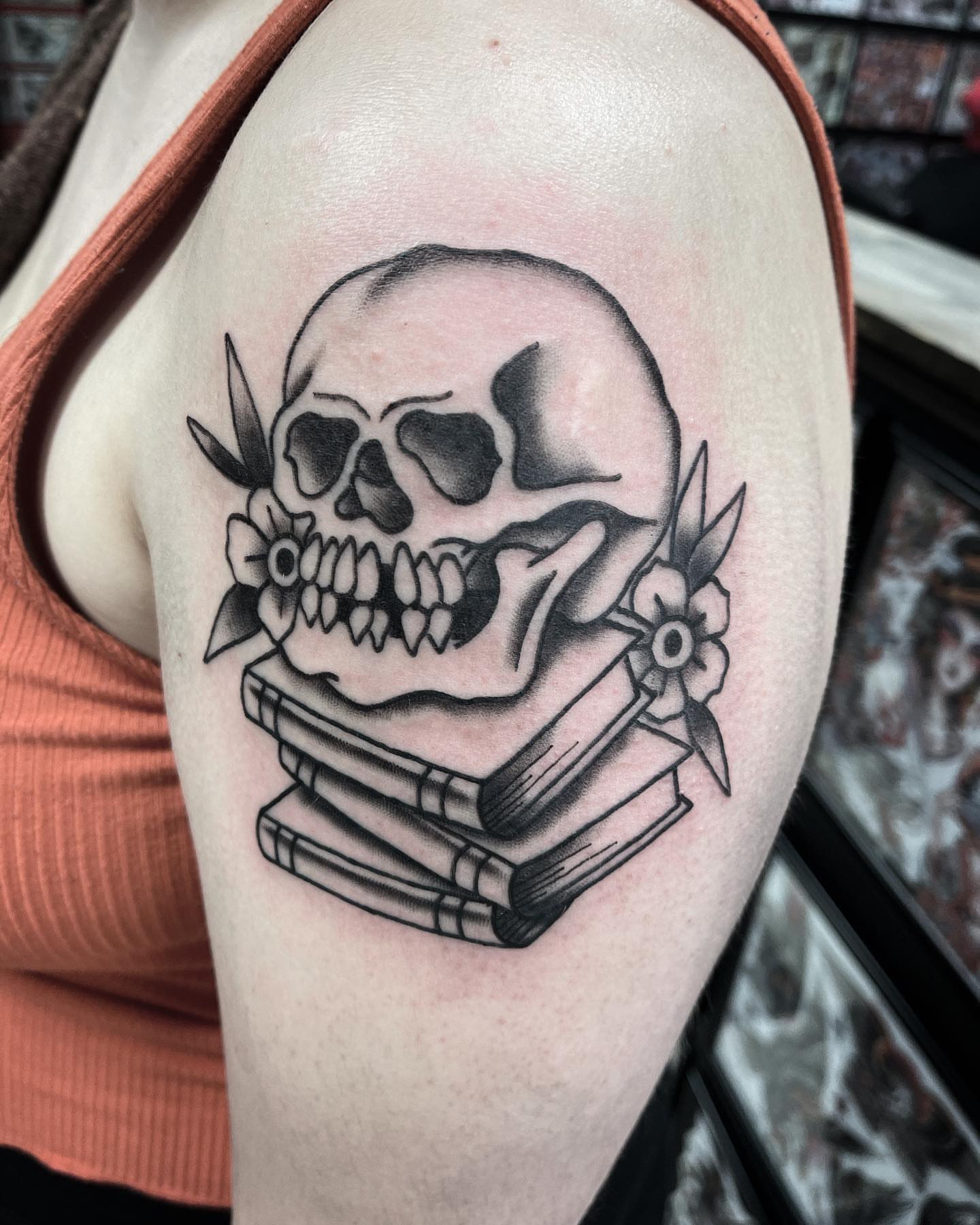 Skull with books American traditional tattoo on the shoulder by Jake Snoddy, Franklin, Tennessee