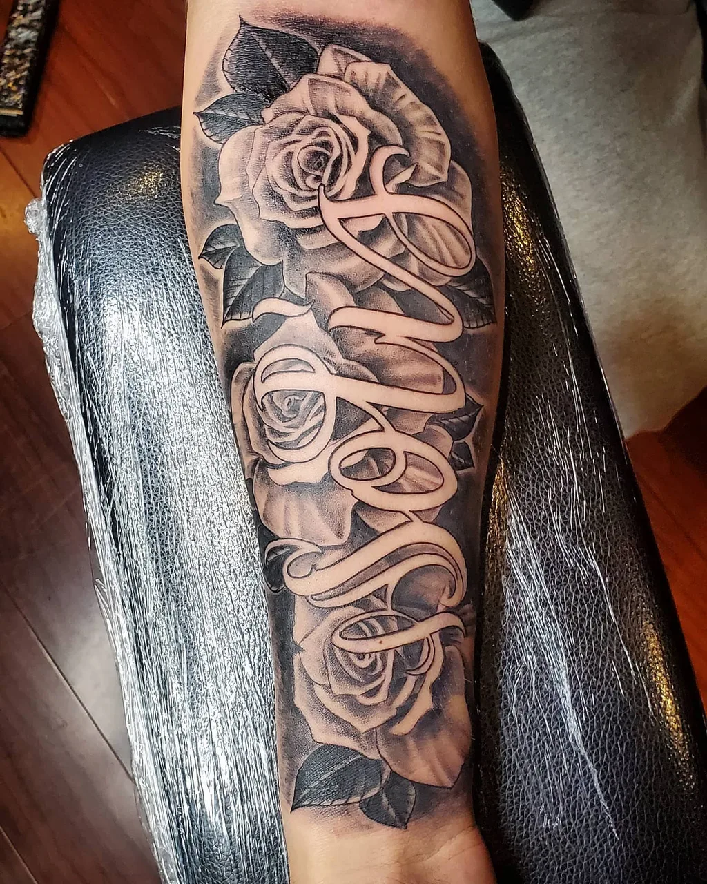 Roses and cursive script realism tattoo on the forearm by David Xavier Jimenez