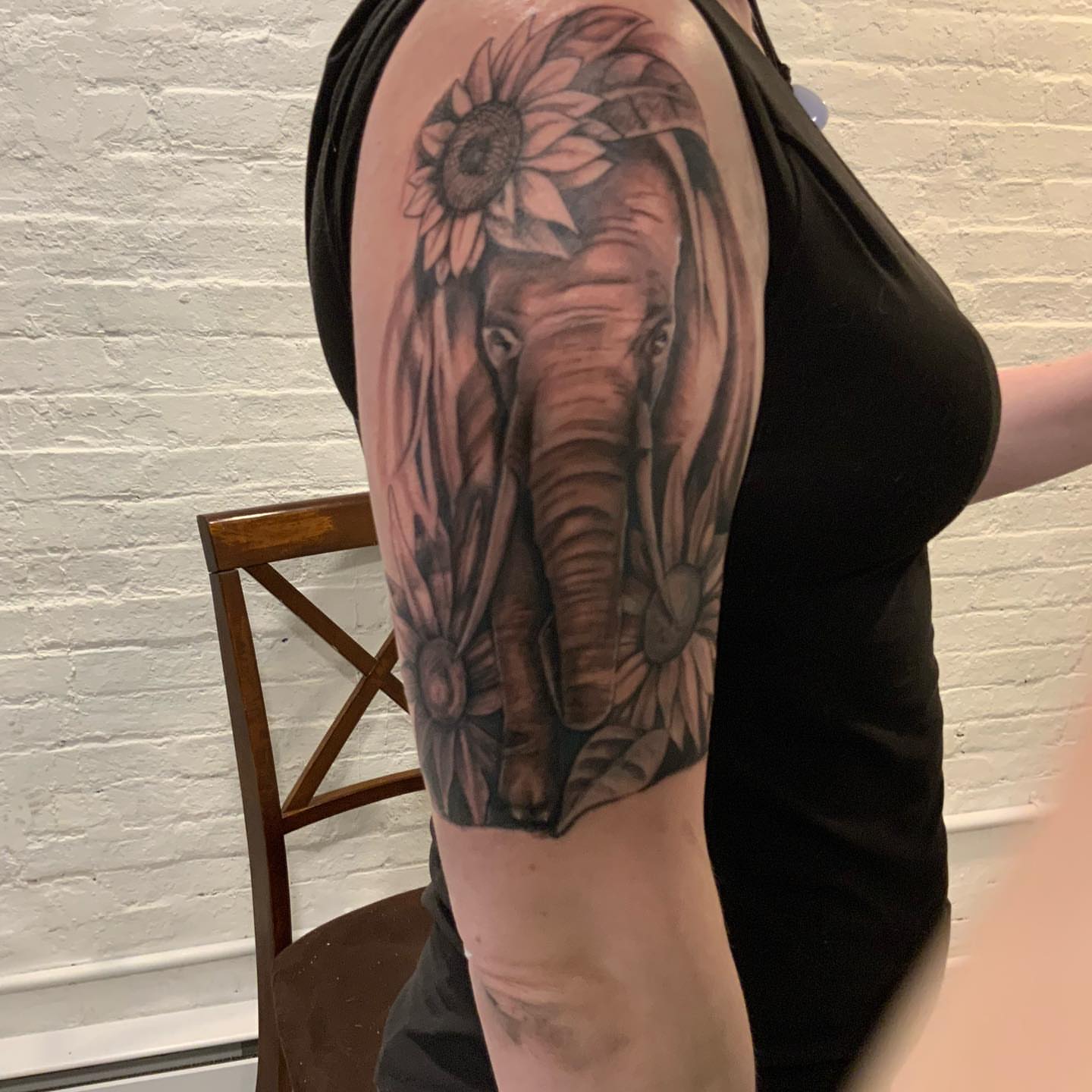 Elephant and sunflower realism tattoo on the upper arm by Daniel Illachek