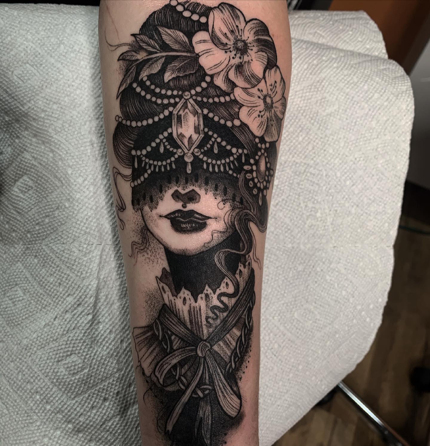 Woman with floral headdress dotwork tattoo on the forearm by Briana Walker