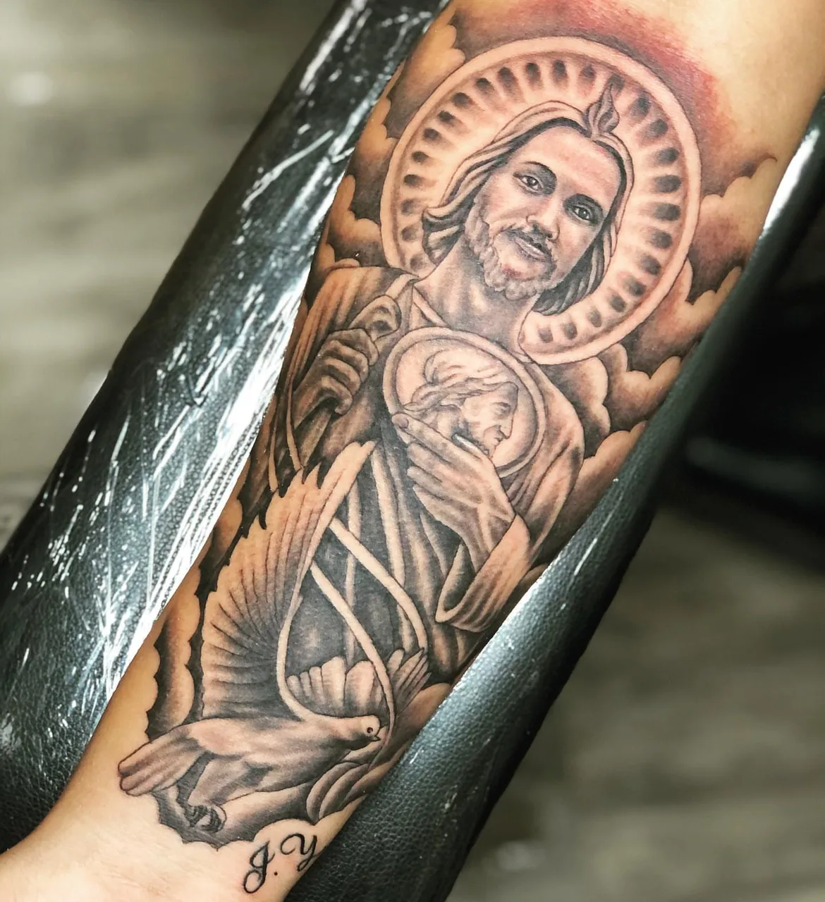 Religious figure with dove realism tattoo on the forearm by Charlie Soto