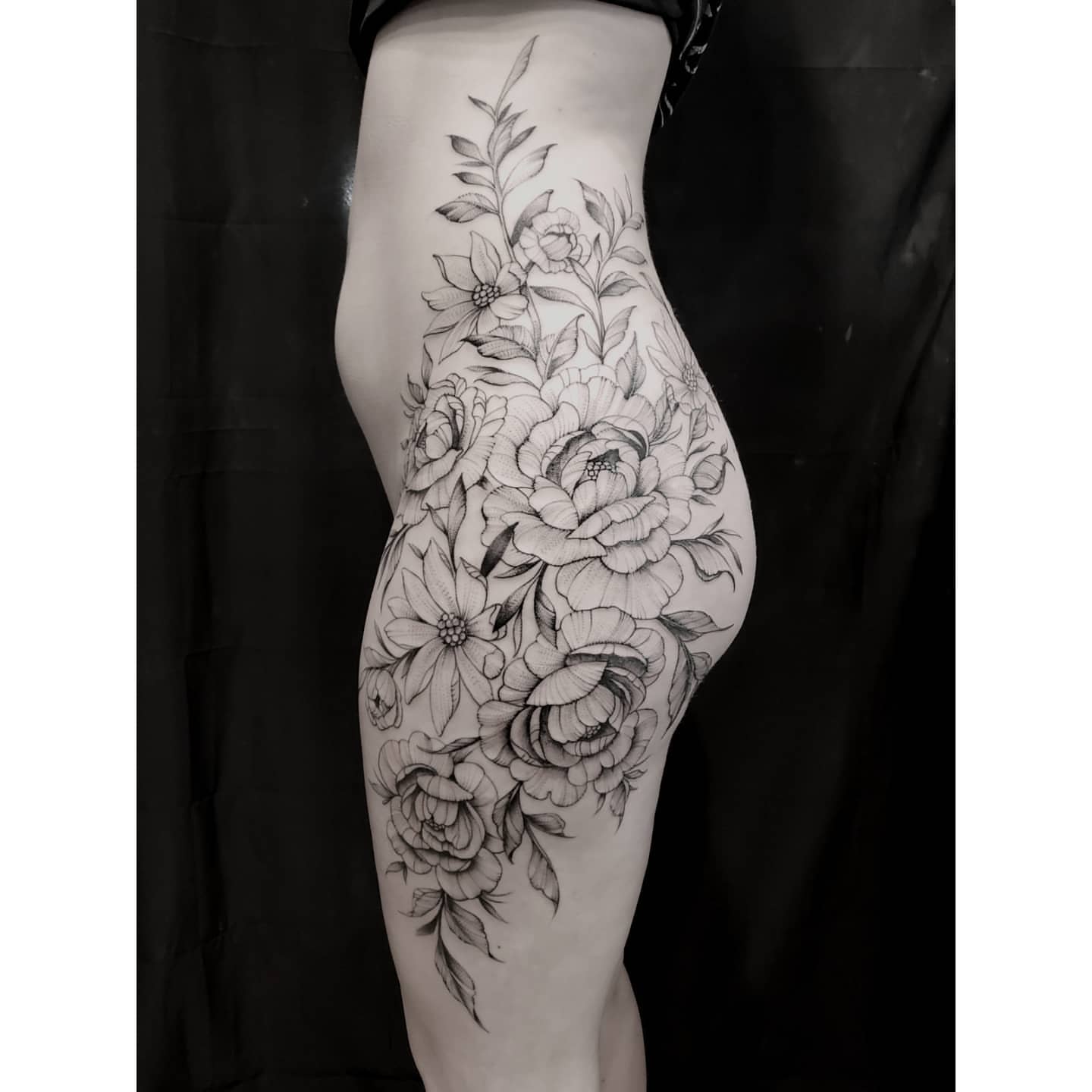 Floral bouquet black and grey tattoo on the thigh by Neil Ohmie