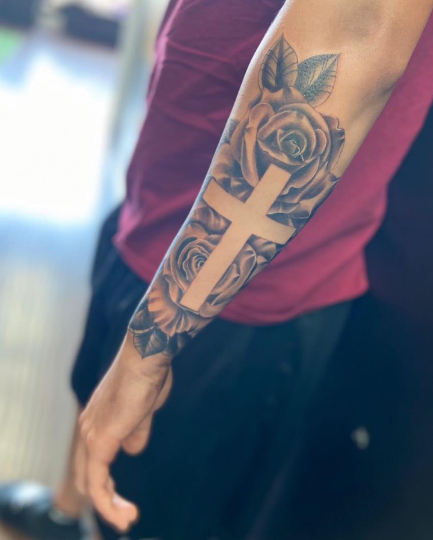 Cross and roses black and grey tattoo on the forearm by Bree Quirino