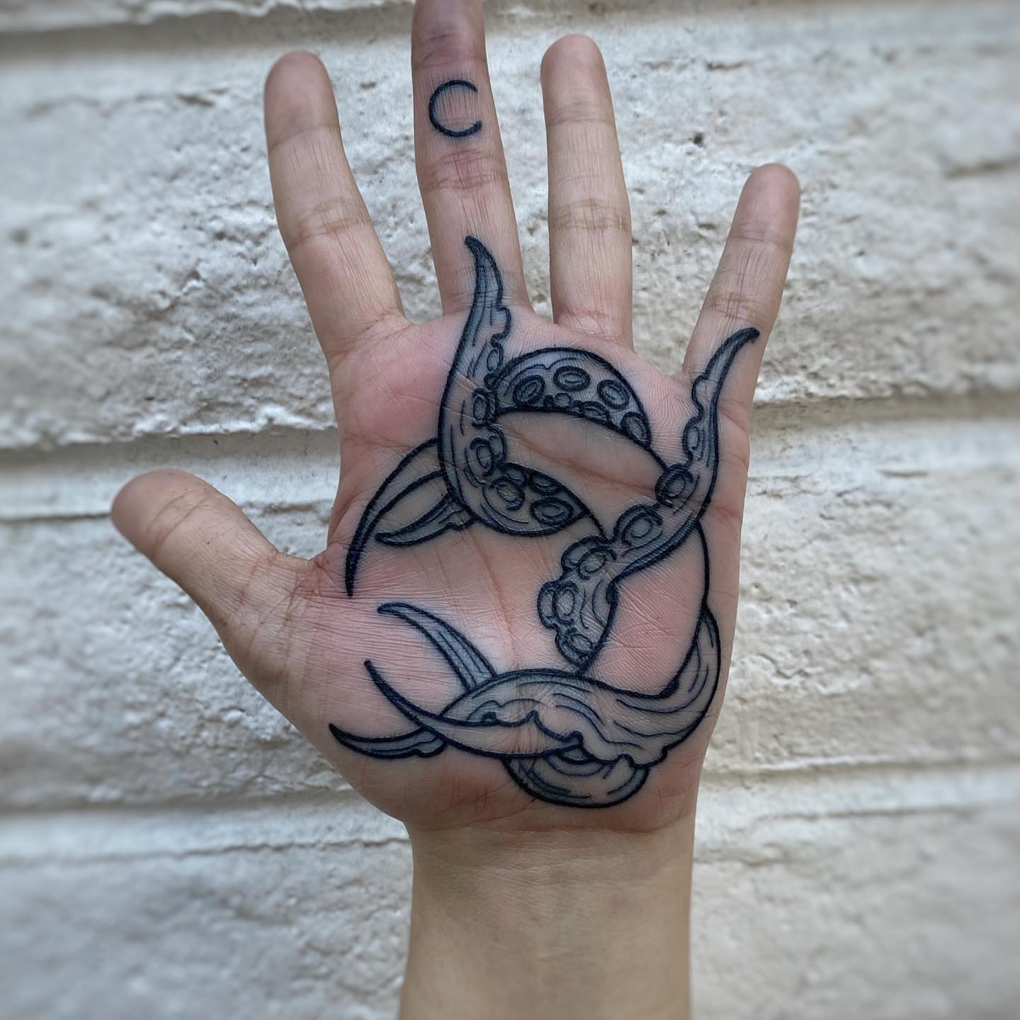 Octopus black and grey tattoo on the hand by Mark Walker