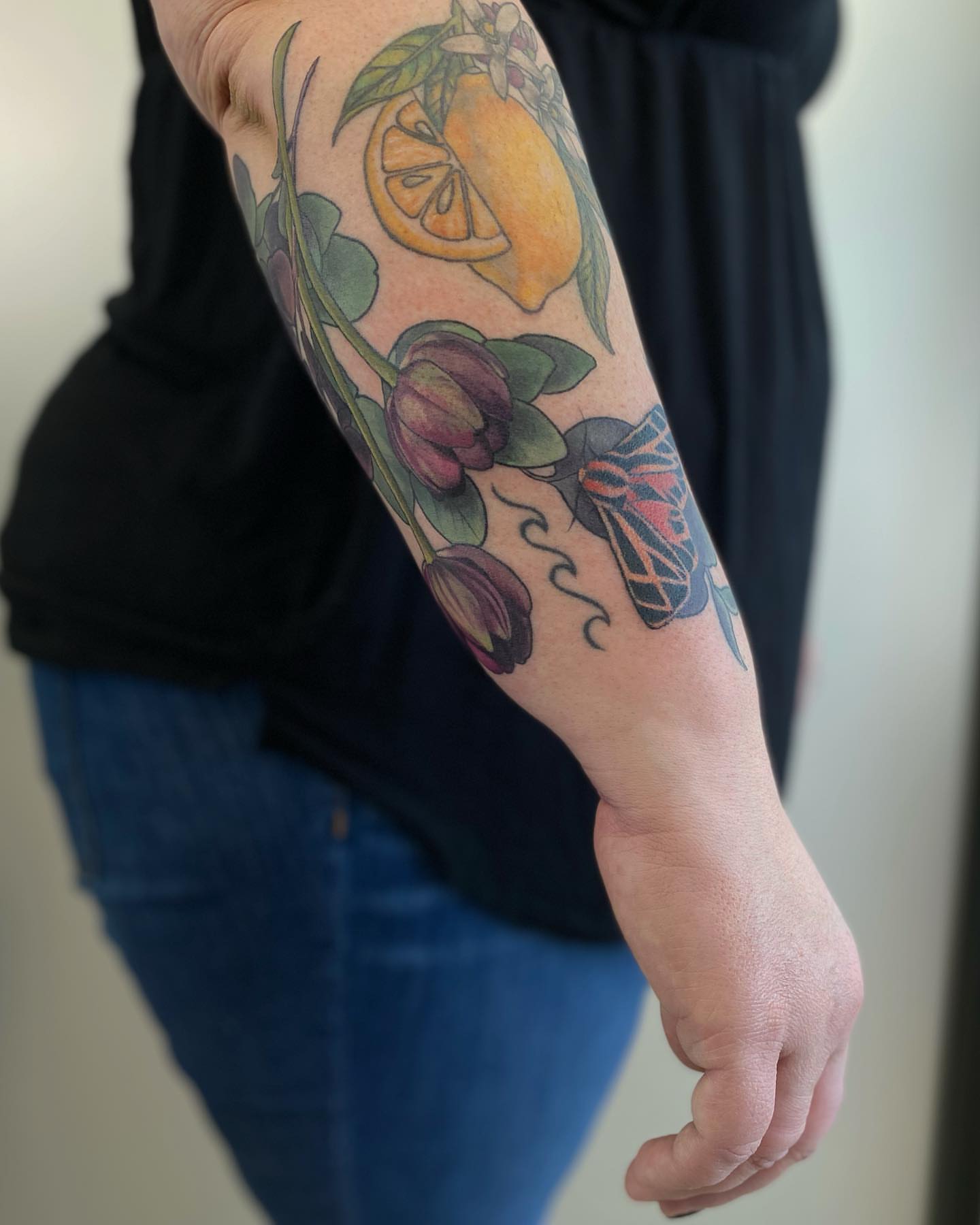 Lemon and tulips realism tattoo on the forearm by Rusty Indigo