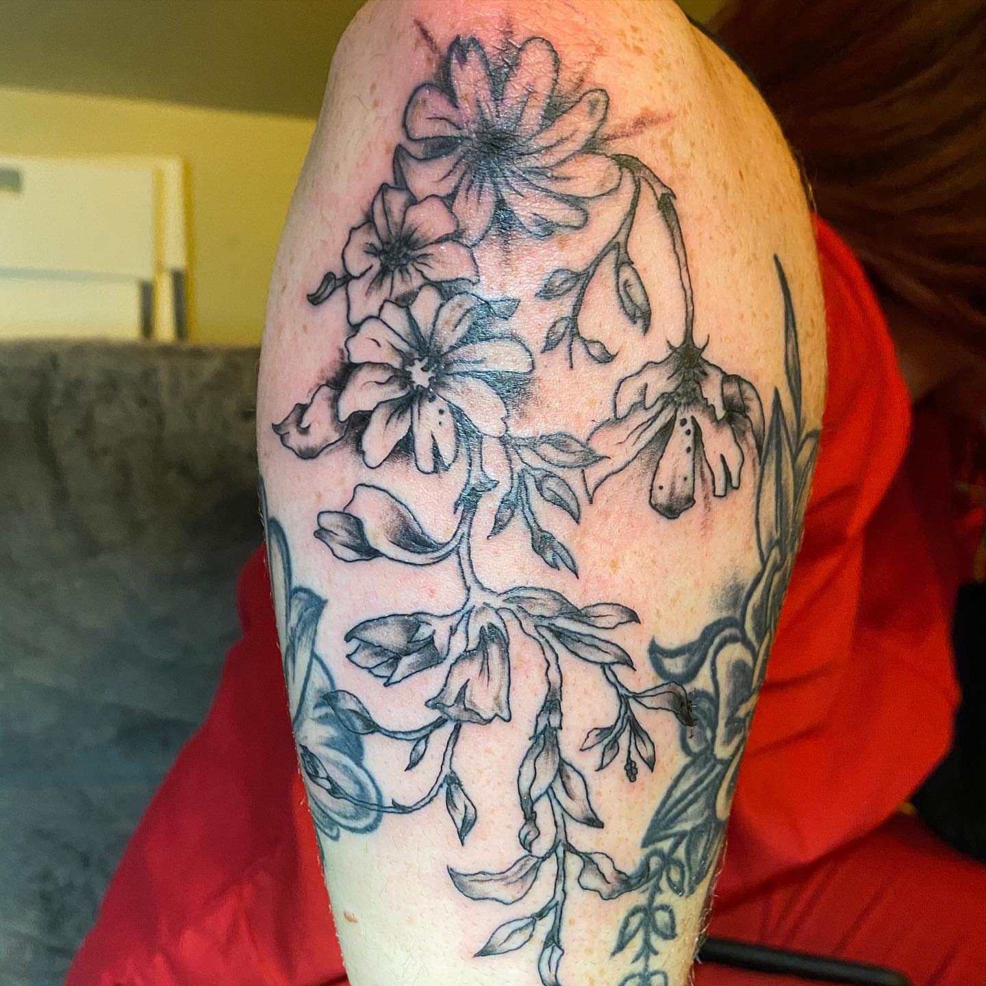 Floral bouquet black and grey tattoo on the upper arm by Nick