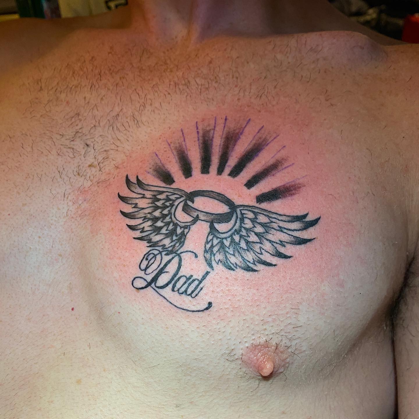 Wings and ring black and grey tattoo on the chest by Nick