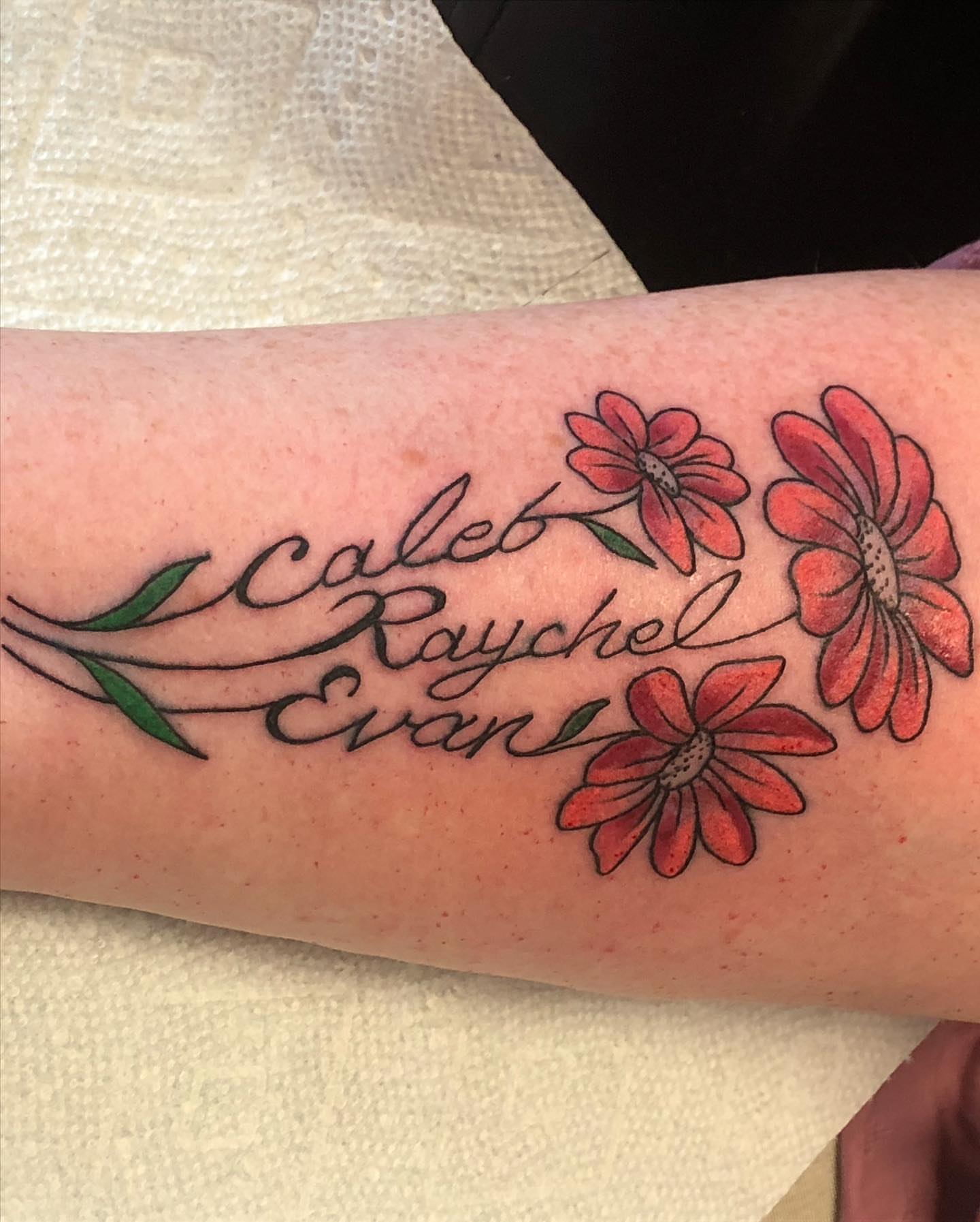 Names and flowers lettering script tattoo on the forearm by Strange Brew Tattoo